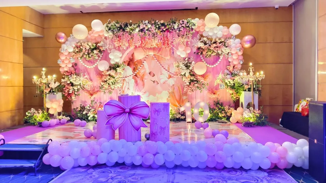 Floral birthday stage with pastel drapes, candelabra and a balloon border set up by Insight Eventz in Lucknow