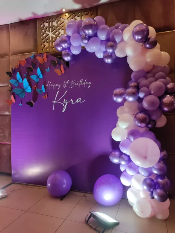 Purple first birthday backdrop with 3D butterflies and a chrome balloon garland