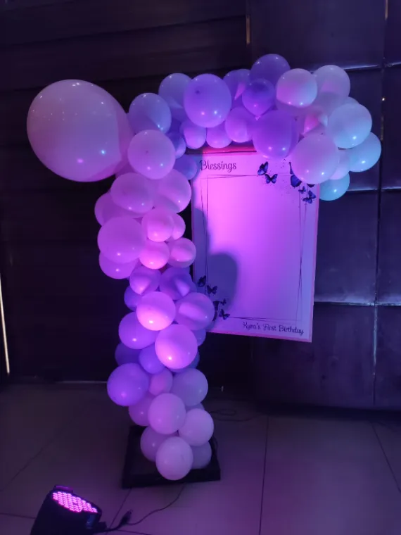 First birthday blessings signing board framed by a lilac balloon garland
